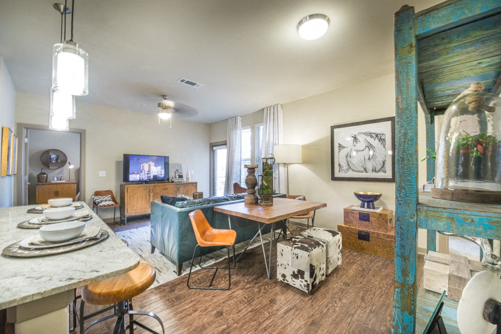 A living room with a TV, a table, chairs and a painting on the wall.