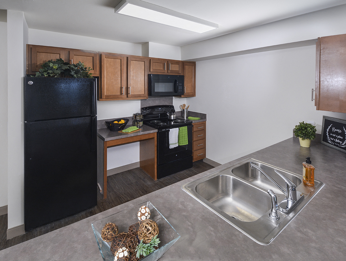 A kitchen with a black fridge, microwave, and stove top oven.