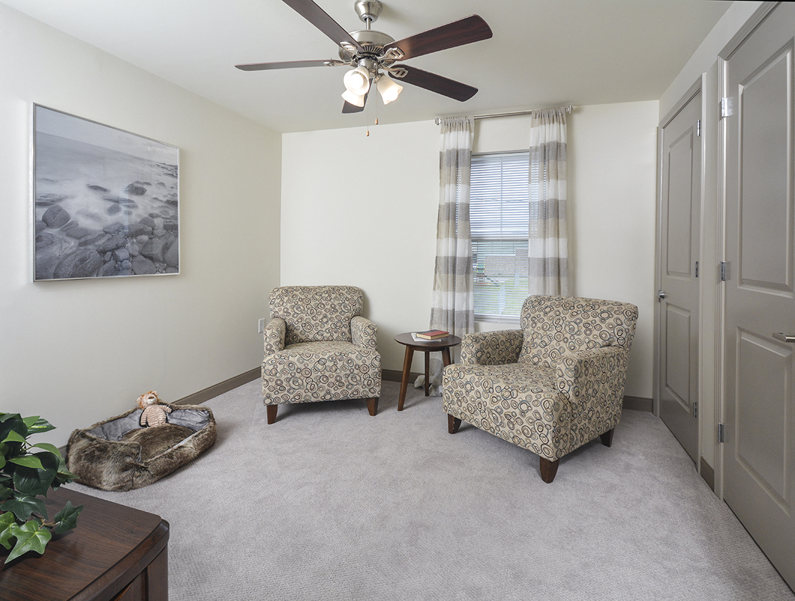 A living room with two chairs and a ceiling fan.