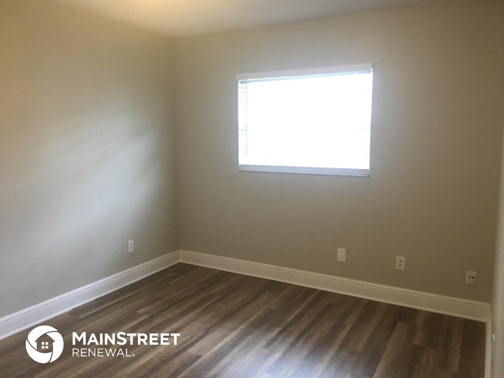 an empty room with a window and wooden floors
