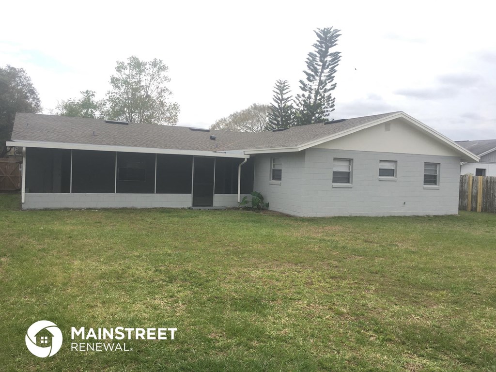 a small white house with a grassy yard and a fence