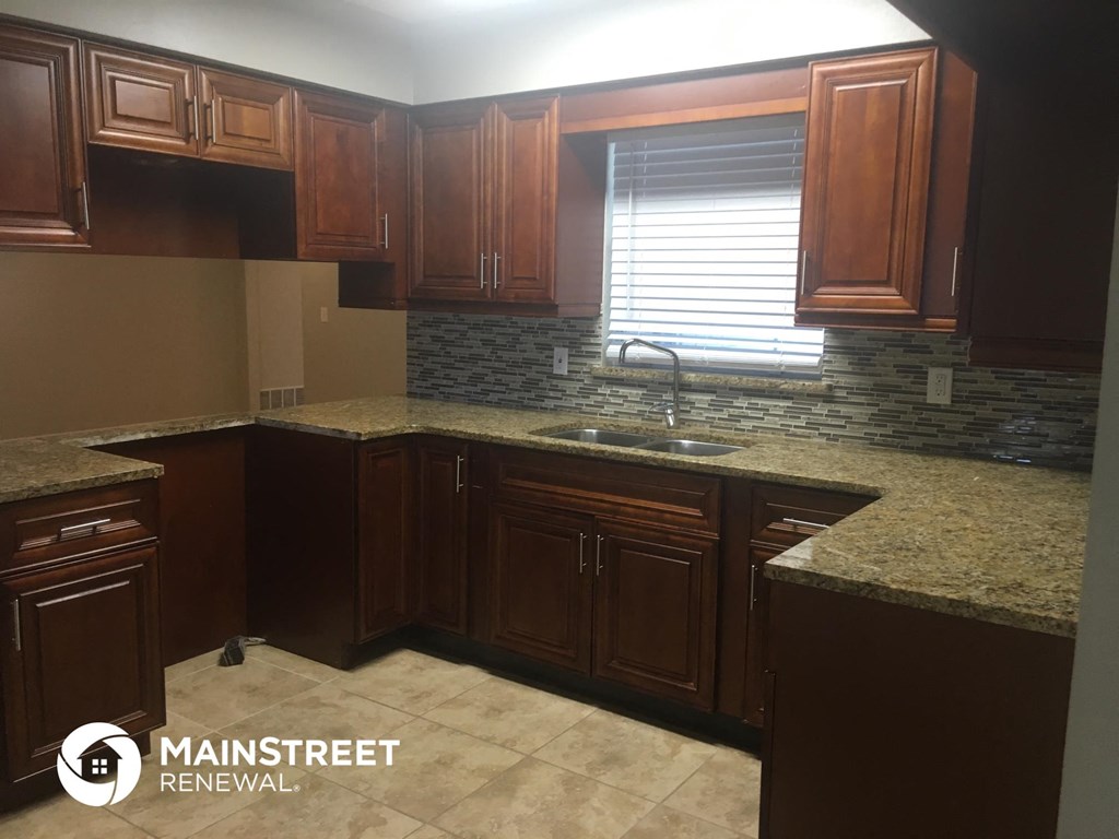 a kitchen with wooden cabinets and granite counter tops and a sink