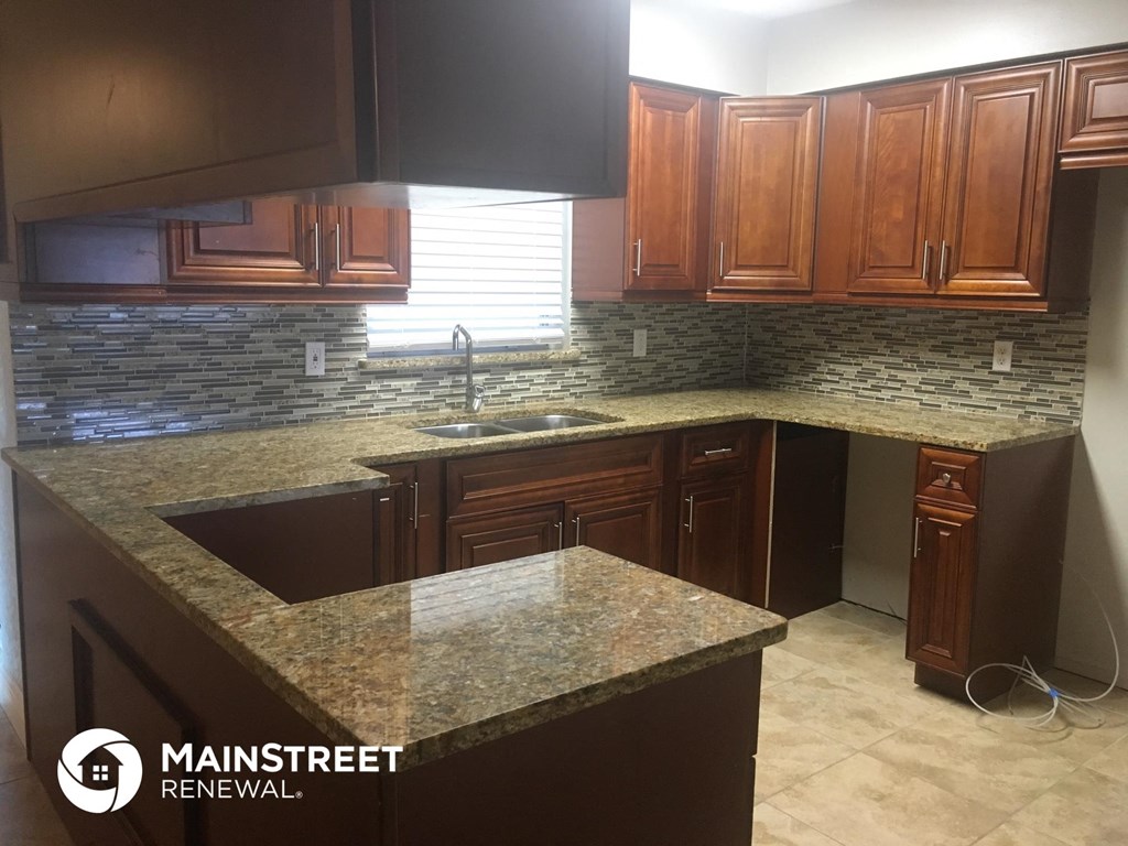 a kitchen with dark wood cabinets and granite counter tops
