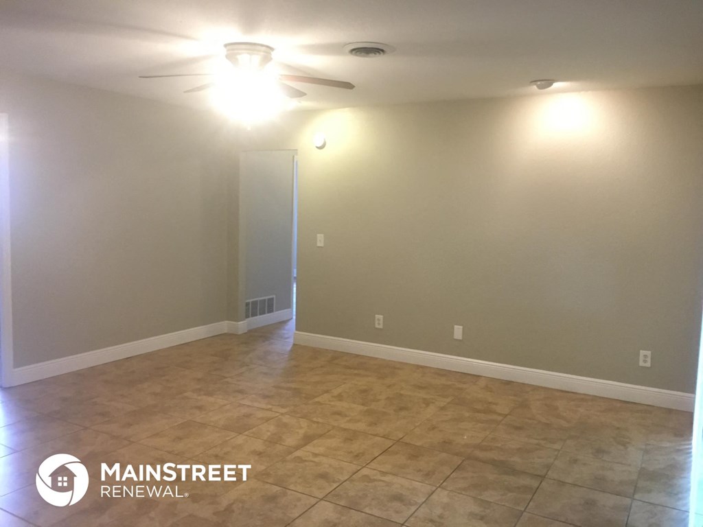 an empty living room with a ceiling fan and a tiled floor