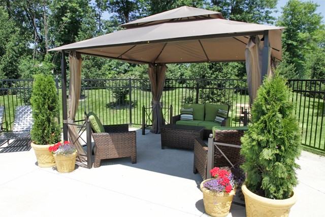 a patio with a gazebo and chairs and potted plants