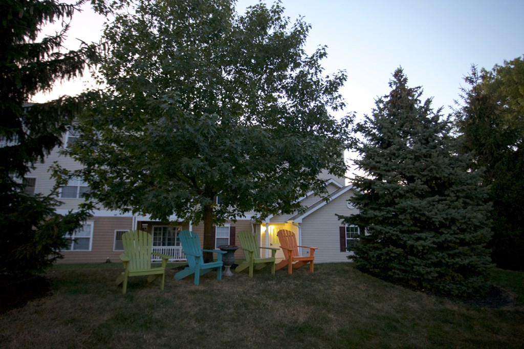 a group of chairs sitting under a tree in front of a house