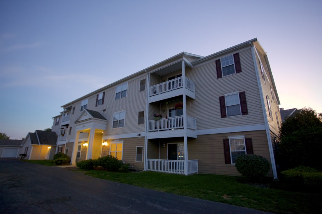 an apartment building at dusk with the lights on in it