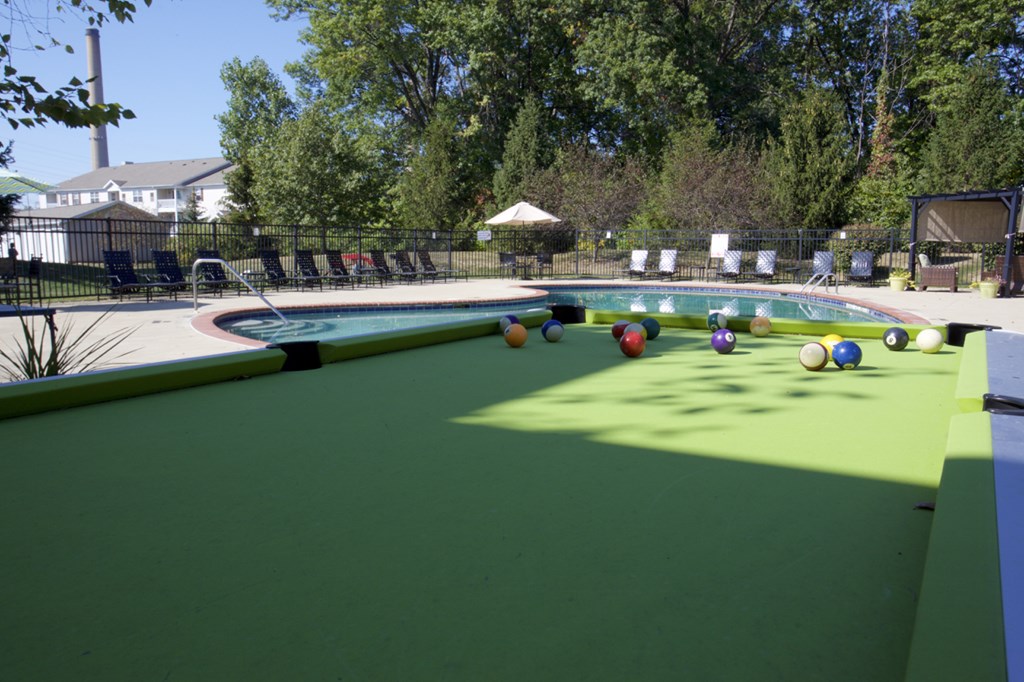 a pool table with balls on it next to a swimming pool