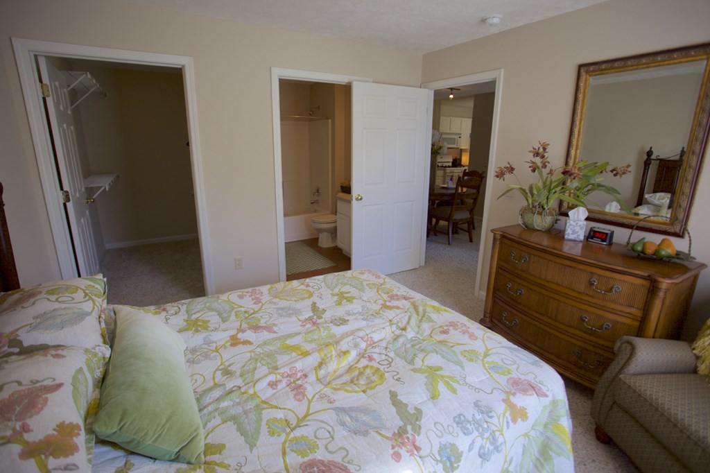 a bedroom with a bed and a dresser and a bathroom