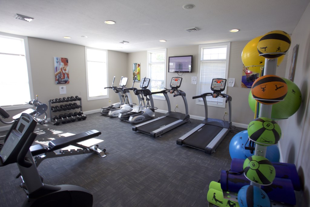 a workout room with cardio equipment and windows in a building