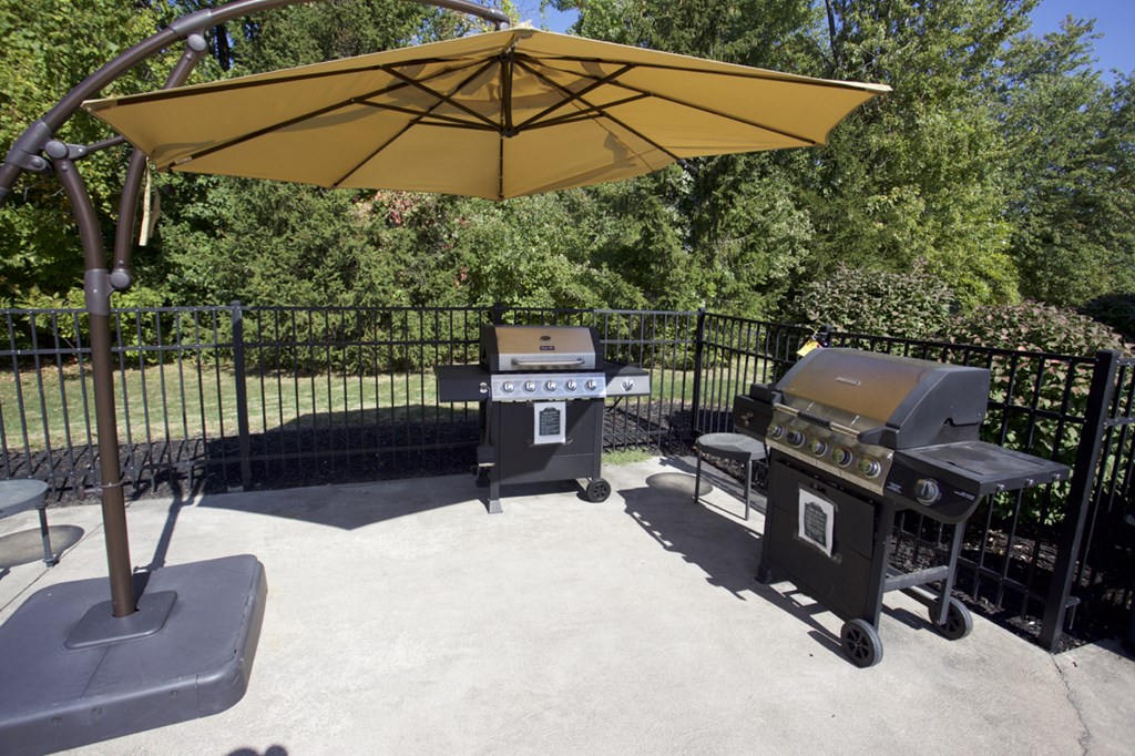 a patio with two gas grills and an umbrella