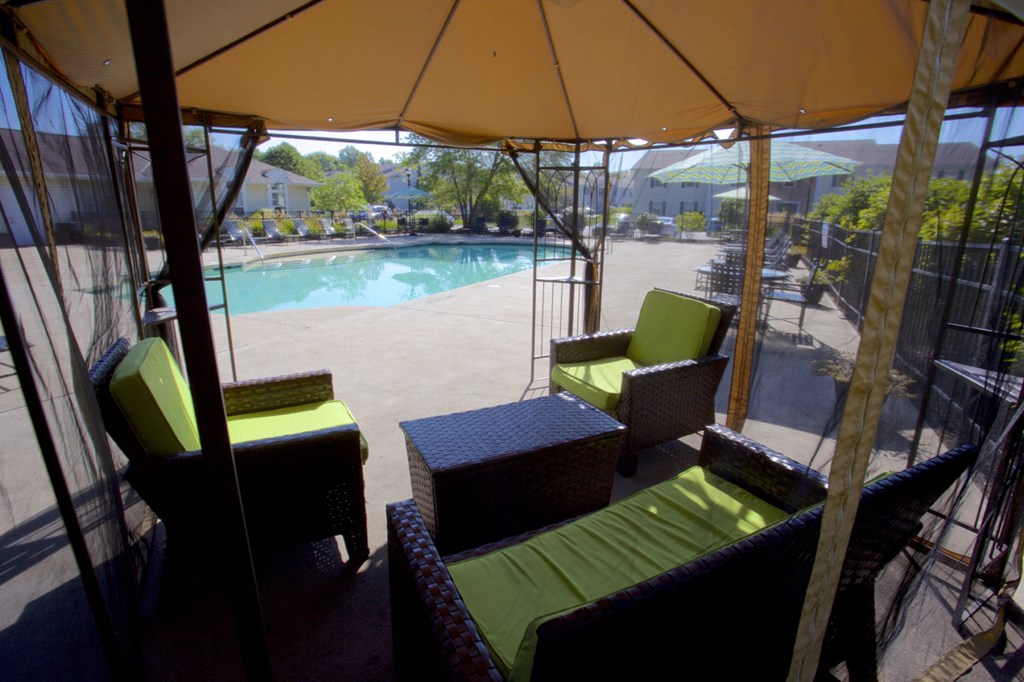 a gazebo with chairs and a table next to a pool