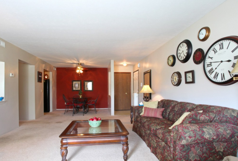 a living room with a couch and a coffee table and clocks on the wall