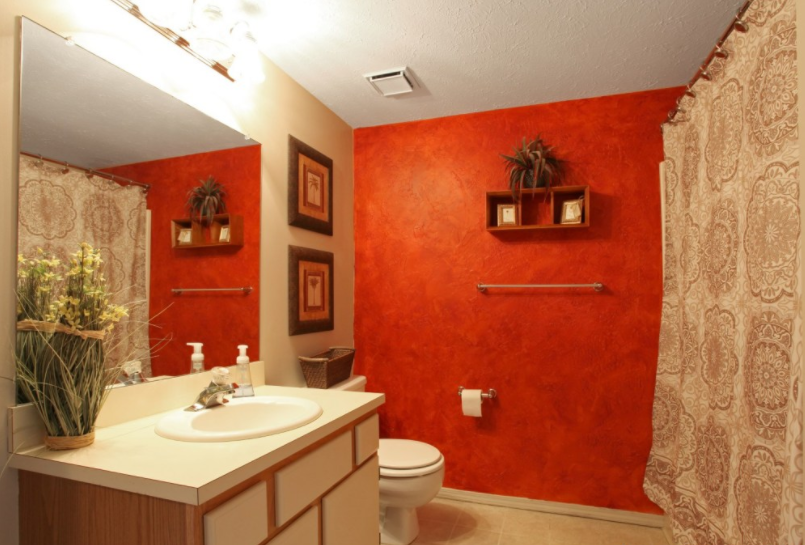a bathroom with a red wall and a sink and a toilet