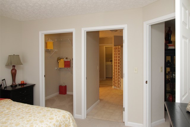 a bedroom with three doors and a closet and a bed