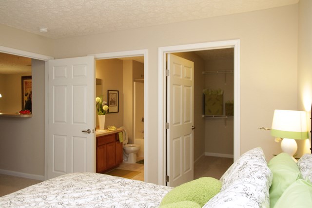 a bedroom with a bed and a bathroom with the door open