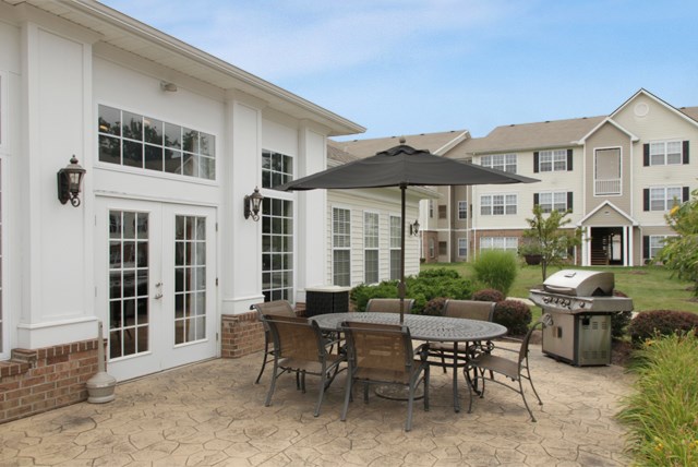 a patio with a table and chairs and a grill