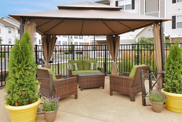 an outdoor patio with a gazebo and wicker furniture