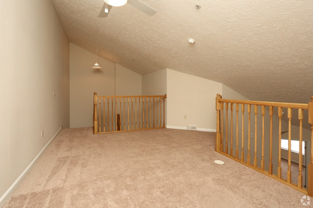 the loft of a house with a crib and a staircase