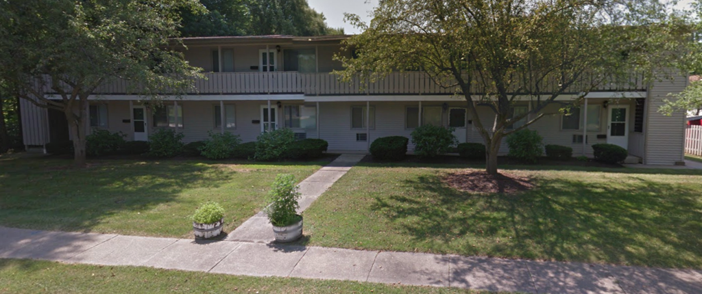 the front of a white house with a yard and trees