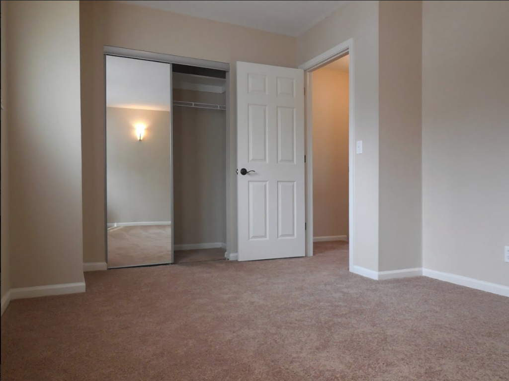 an empty living room with a white door and a closet