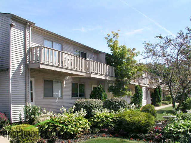 the exterior of an apartment building with a balcony and landscaping