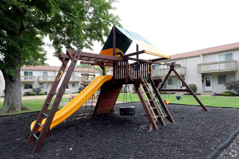 a swing set in a playground in front of an apartment building