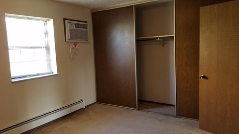a bedroom with a closet and an air conditioner in it