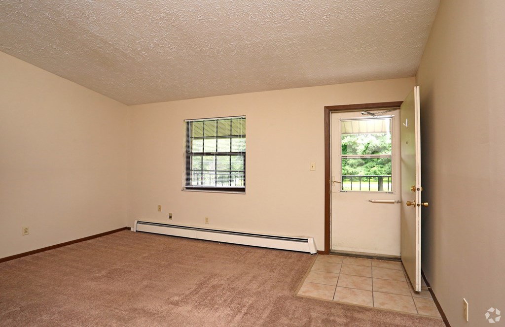 the living room of an empty house with a door and a window