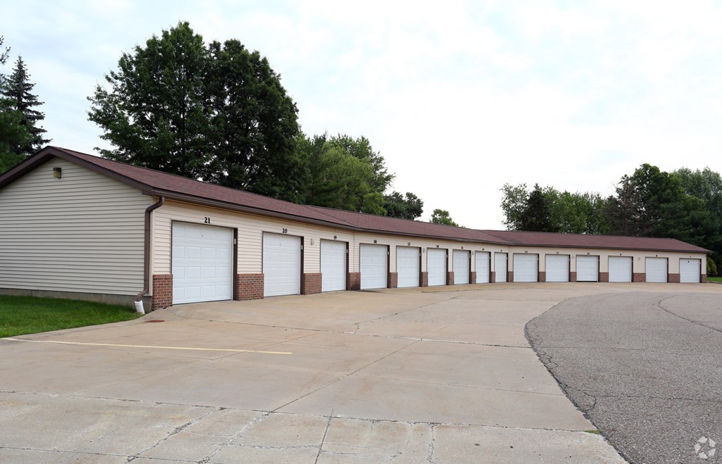 the outside of a building with white garage doors and a parking lot