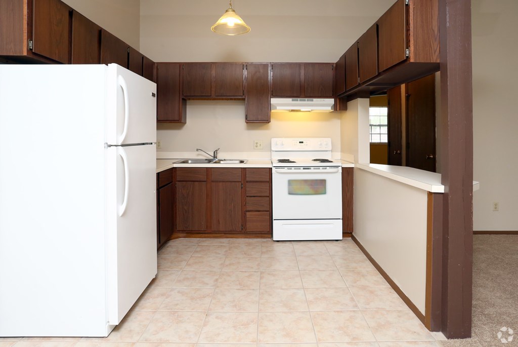 an empty kitchen with white appliances and wooden cabinets