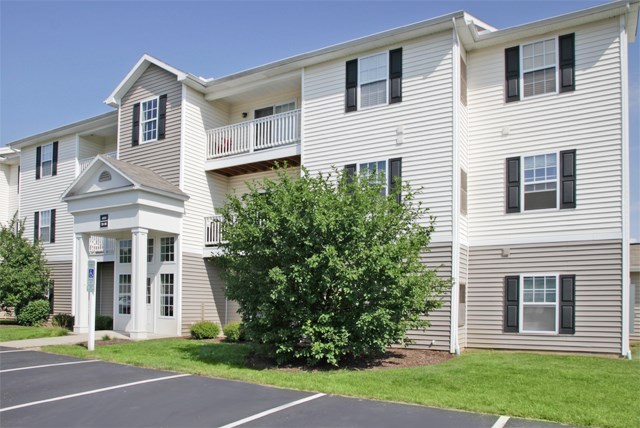 a large white apartment building with a tree in front of it