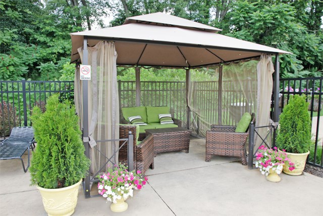 a gazebo with curtains and chairs on a patio