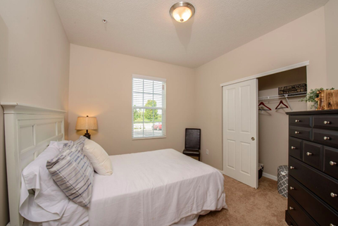 A bedroom with a bed, dresser, and window.