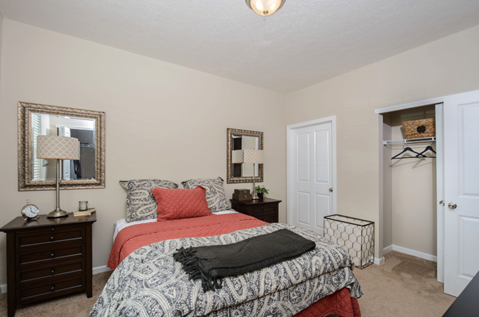 A bedroom with a bed, nightstand, and two mirrors.