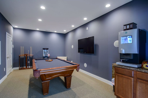 A pool table in a room with a television and a cabinet.