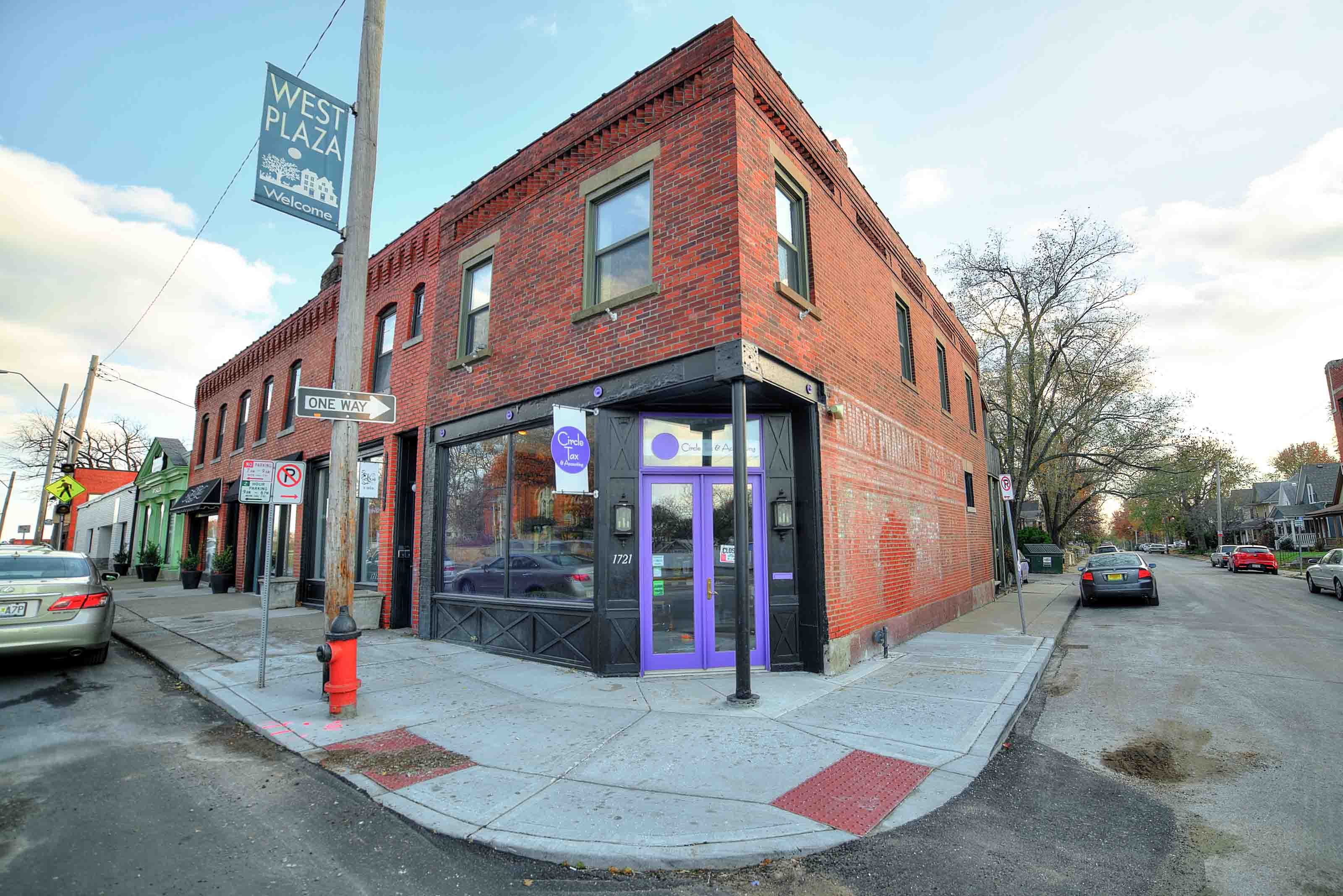 A red brick building with a purple door and a sign that says West Plaza.
