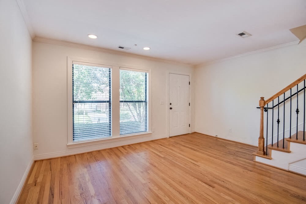 an empty living room with a staircase and a window