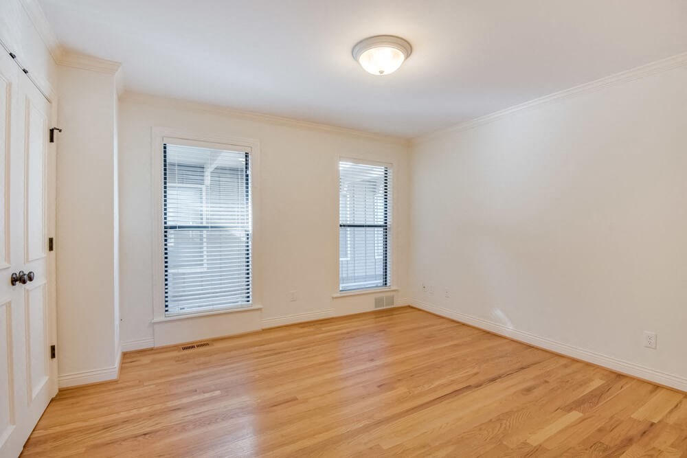 an empty living room with wood flooring and two windows