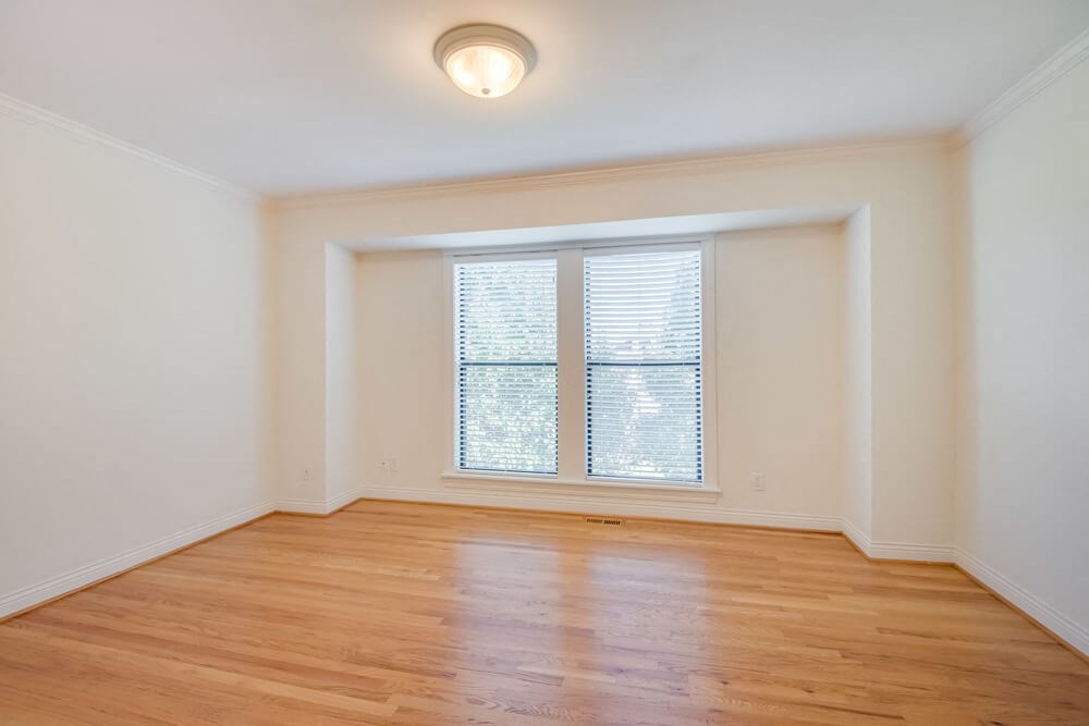 an empty room with a window and wooden floors
