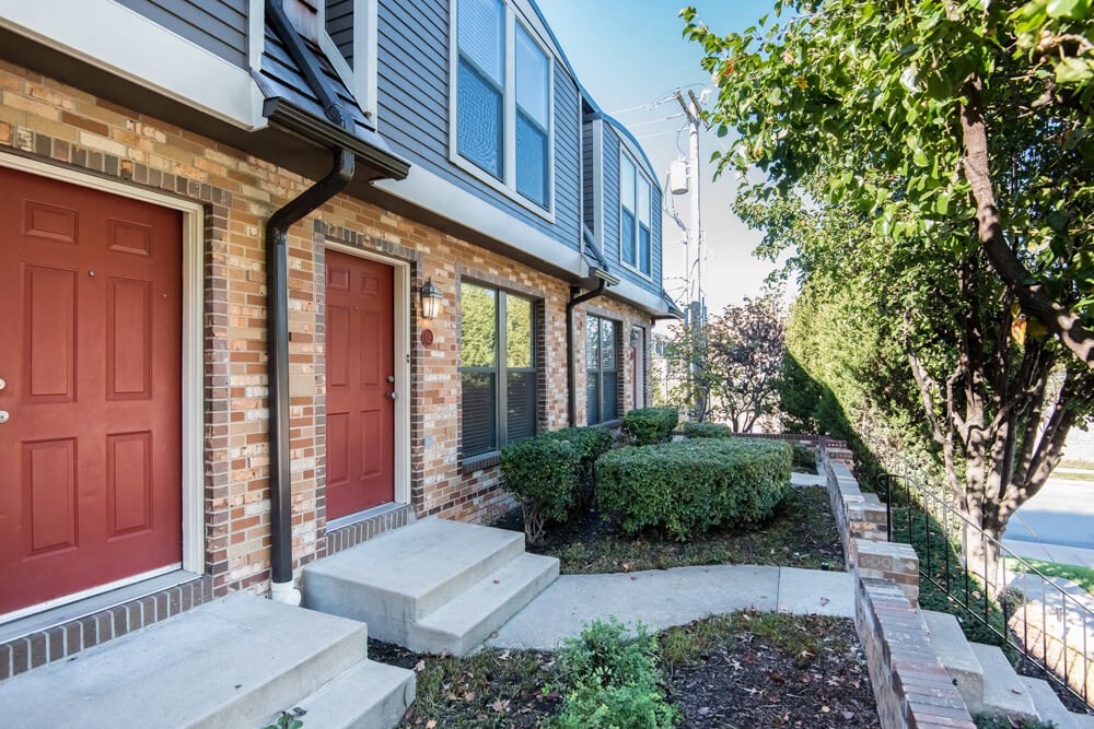 the front of a brick house with two red doors