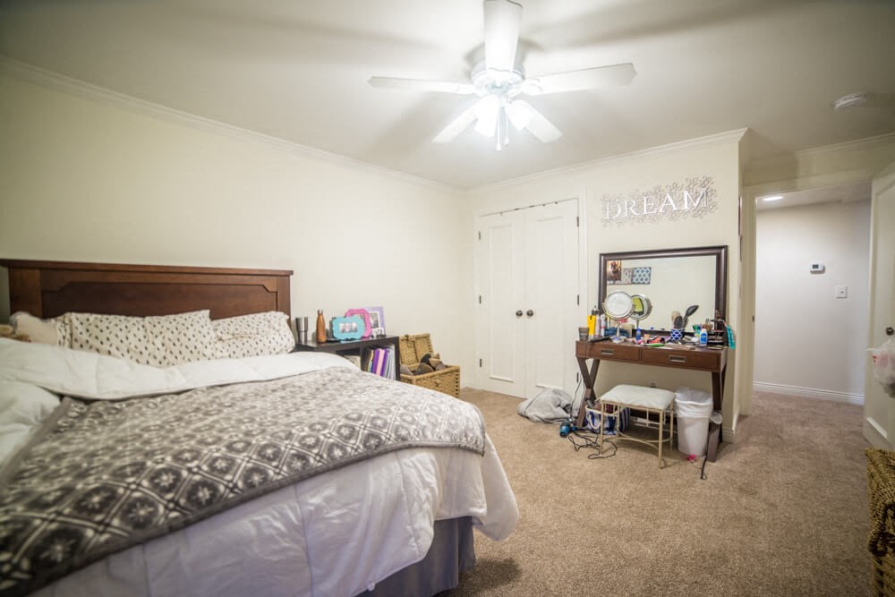 a bedroom with a bed and a desk and a ceiling fan