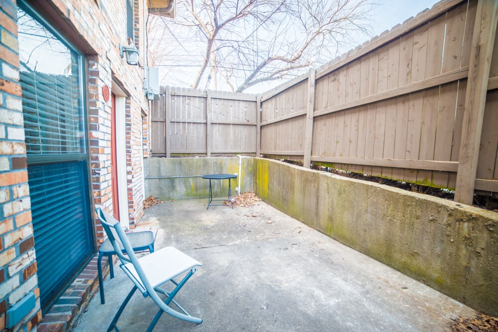 the back patio has a table and chairs and a privacy fence