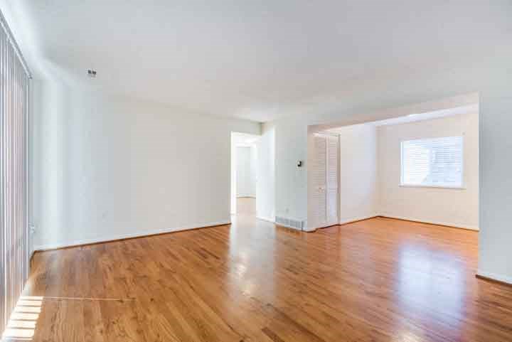 an empty living room with wood floors and white walls