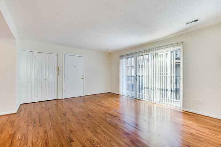 an empty living room with wood floors and a window