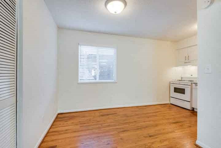an empty living room and kitchen with wood flooring and a window