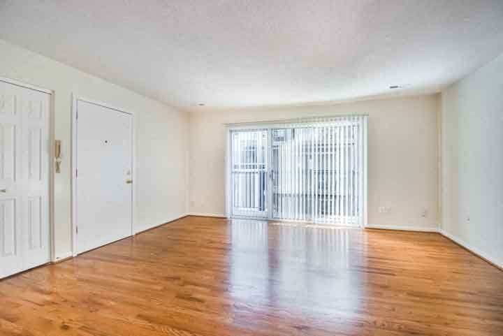an empty living room with wood floors and a sliding glass door