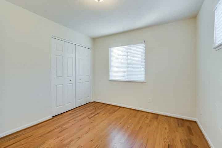 an empty bedroom with a wooden floor and a white door