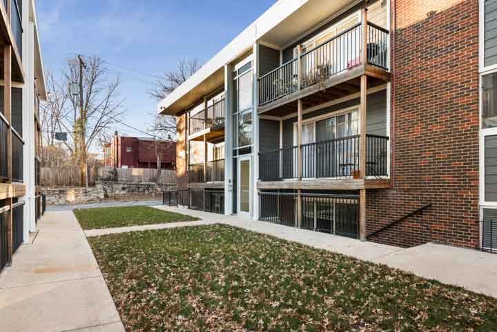 an apartment building with a sidewalk and grass