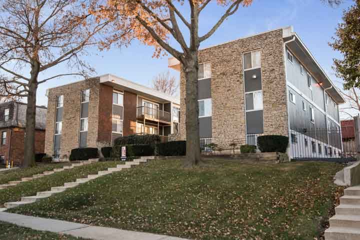 an apartment building with stairs and a yard in front of it